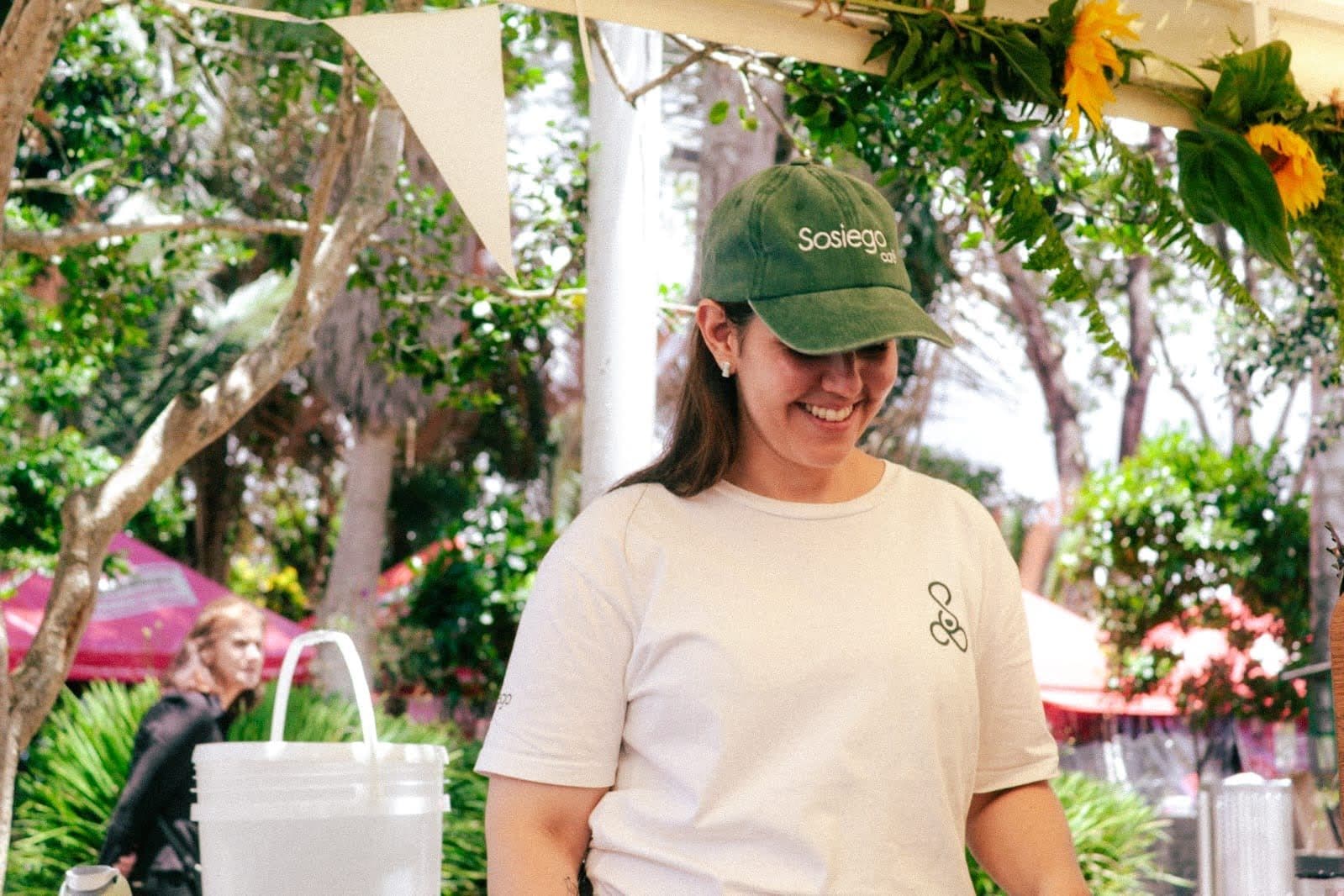 A member of the Sosiego team smiles at the counter, wearing the brand's green cap