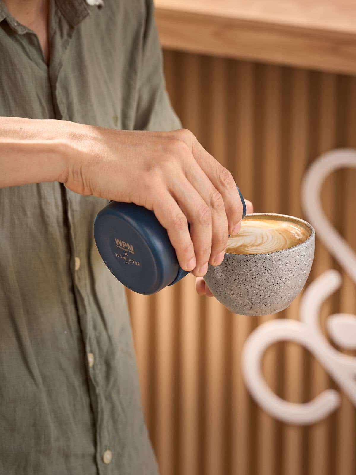 Un barista sirve un latte con arte en una taza de cerámica