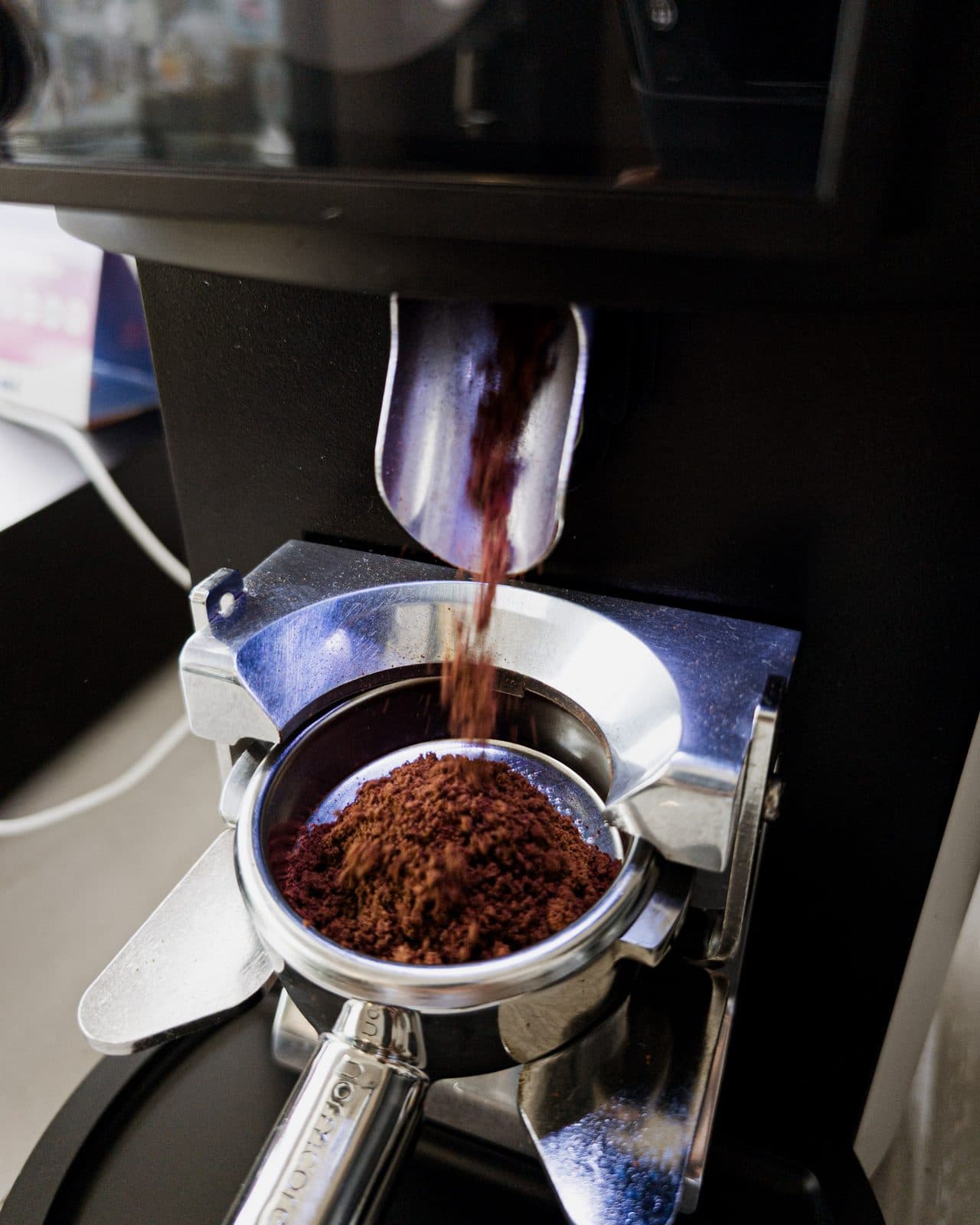 The grinder drops freshly ground coffee into the portafilter